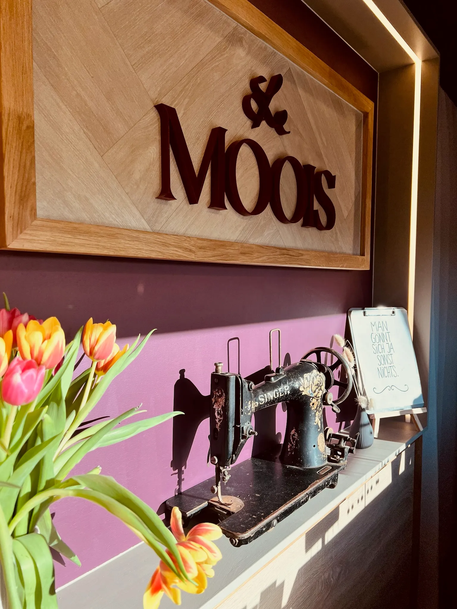 Le-Moois-Schild über Nähmaschine mit Tulpenstrauß in der Werkstatt
